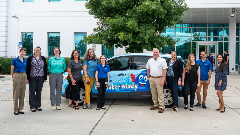 People standing infront of a car with a water conservation message